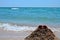 Big waves on the beach, ocean. Red and orange sunglasses lying on a sand slide built by a child on the beach