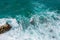 Big waves breaking on the shore. Waves and white foam. Coastal stones. View from above. The marine background is green