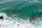 Big waves breaking on the shore. Waves and white foam. Coastal stones. View from above. The marine background is green