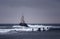 Big waves crashing at lighthouse. Dark and stormy weather at Ahtopol, Bulgaria and a surfer.