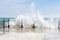 Big waves crushing on curved stone pier, on sunnny weather, big tide.