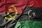 big waving national colorful flag of angola and national flag of libya