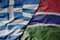 big waving national colorful flag of greece and national flag of gambia