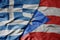 big waving national colorful flag of greece and national flag of puerto rico