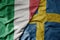 big waving national colorful flag of italy and national flag of sweden