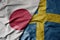 big waving national colorful flag of japan and national flag of sweden