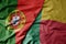 big waving national colorful flag of portugal and national flag of benin