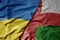 big waving national colorful flag of ukraine and national flag of oman