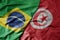 big waving realistic national colorful flag of brazil and national flag of tunisia