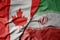 big waving realistic national colorful flag of canada and national flag of iran