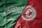 big waving realistic national colorful flag of saudi arabia and national flag of tunisia