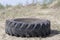 Big wheel from a truck lying on a plain overgrown with shrubs