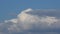 Big white cumulus or cumulonimbus cloud changing against blue sky in time-lapse