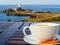 Big white cup on a table and seacoast as a background