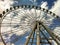 A big white ferris wheel, seen from below, with the blue sky, full of white clouds. Concept of greatness and fun