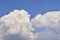 Big white fluffy cumulonimbus clouds floating on blue sky on bright sunny day.