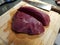 Big wild game meat cut in half on a wooden cuttingboard with big sharp kitchen knife