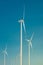 Big wind turbines to generate electrical power, green ecofriendly energy at blue sky standing in arid lifeless soil in warm