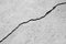 Big winding ascending crack on old gray plastering wall. Thin crack diagonally. Copy space. Black and white photo. Selectiv