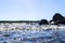 Big windy waves splashing over rocks. Wave splash in the lake against beach. Waves breaking on a stony beach, forming a spray. Wat