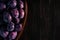 Big wooden bowl of ripe juicy purple plums on a wooden table