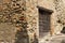 Big wooden door near a corner of a medieval brick building Fiorenzuola di Focara, Italy, Europe