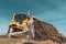 A big yellow bulldozer pushes the ground and makes a new road