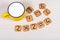 Big yellow cup of milk and funny cookies with numbers on light wooden background. Healthy breakfast for a child.