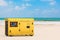 Big Yellow Outside Auxiliary Electric Power Generator Diesel Unit for Emergency Use on an Ocean or Sea Summer Beach. 3d Rendering