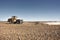 Big yellow tractor equipped with harrow working on the field