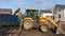 A big yellow tractor loads construction garbage into a container with a bucket and press it