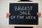 Biggest sale of the week written on blackboard. Black friday concept. Boy hold board