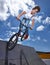 Bike, jump and teen on ramp for sport performance, ride or training for event at park with sky. Bicycle, stunt or kid