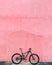 Bike leaned against a pink wall backgrond, vertical shot