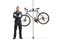 Bike mechanic standing next to a bicycle hanging on a stand