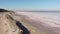 Bike rider is sitting on the edge of seashore of salty lake with pink water Kuyalnik, aerial drone view. Incredible beautiful natu