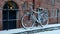 Bike stands under a brick wall in the snow in the winter