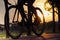 Bike at the summer sunset on road in city park. Cycle closeup wheel on blurred light at summer.