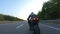 Biker is accelerating at motorcycle on empty country road. Man riding fast on modern sport motorbike at autumn highway