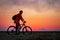 Biker with bicycle on the field at sunrise