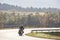 Biker in black leather outfit driving modern powerful motorcycle along sunny road on summer day.