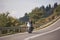 Biker in black leather outfit driving modern powerful motorcycle along sunny road on summer day.