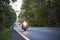 Biker in black leather outfit driving modern powerful motorcycle along sunny road on summer day.