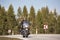 Biker in black leather outfit driving modern powerful motorcycle along sunny road on summer day.