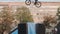 Biker on BMX bicycle jumps and does no foot trick. Old building on background.