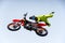 Biker in a protective bright suit and helmet does a stunt jump on a motorcycle on a motocross