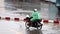 A biker with raincoat ride on a motorcycle at wet street during a heavy rain