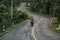 Biker is riding a motorcycle on the road to the top of the hill.