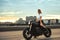 Biker sexy woman sitting on vintage custom motorcycle. Outdoor lifestyle portrait