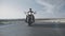 Biker in sunglasses on motorcycle rides along the highway through steppe, low view, front view. Man on motorcycle rides